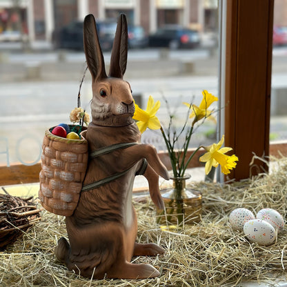 brauner osterhase mit korb und langen ohren ist befüllbar und steht im schaufenster auf stroh