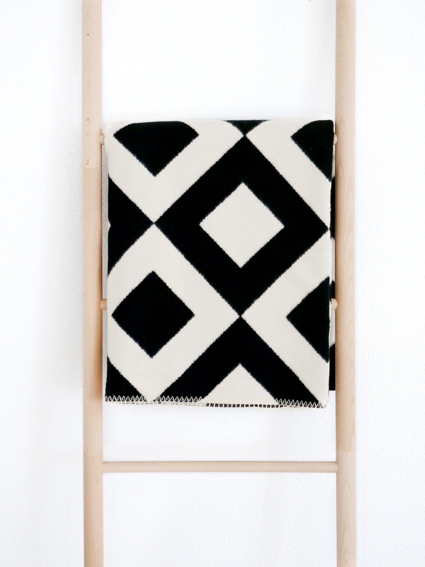 Eine Kuscheldecke aus Baumwolle in schwarz-beige mit Boho Muster.