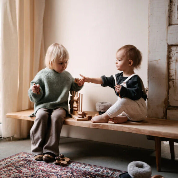 Kinder spielen mit einem Steckspiel aus Holz.